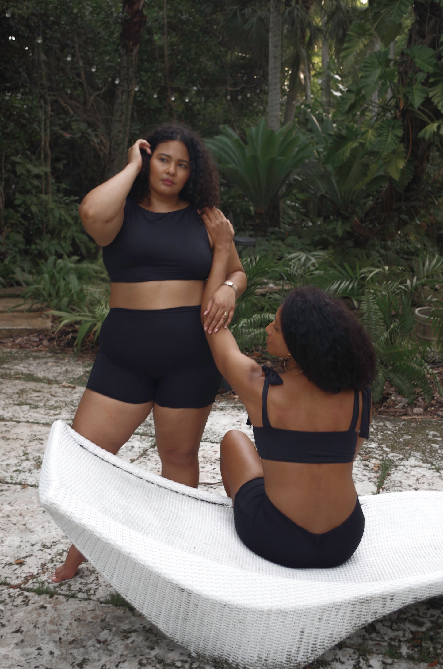 woman wearing cropped black tankini with removable padding and high waisted swim shorts